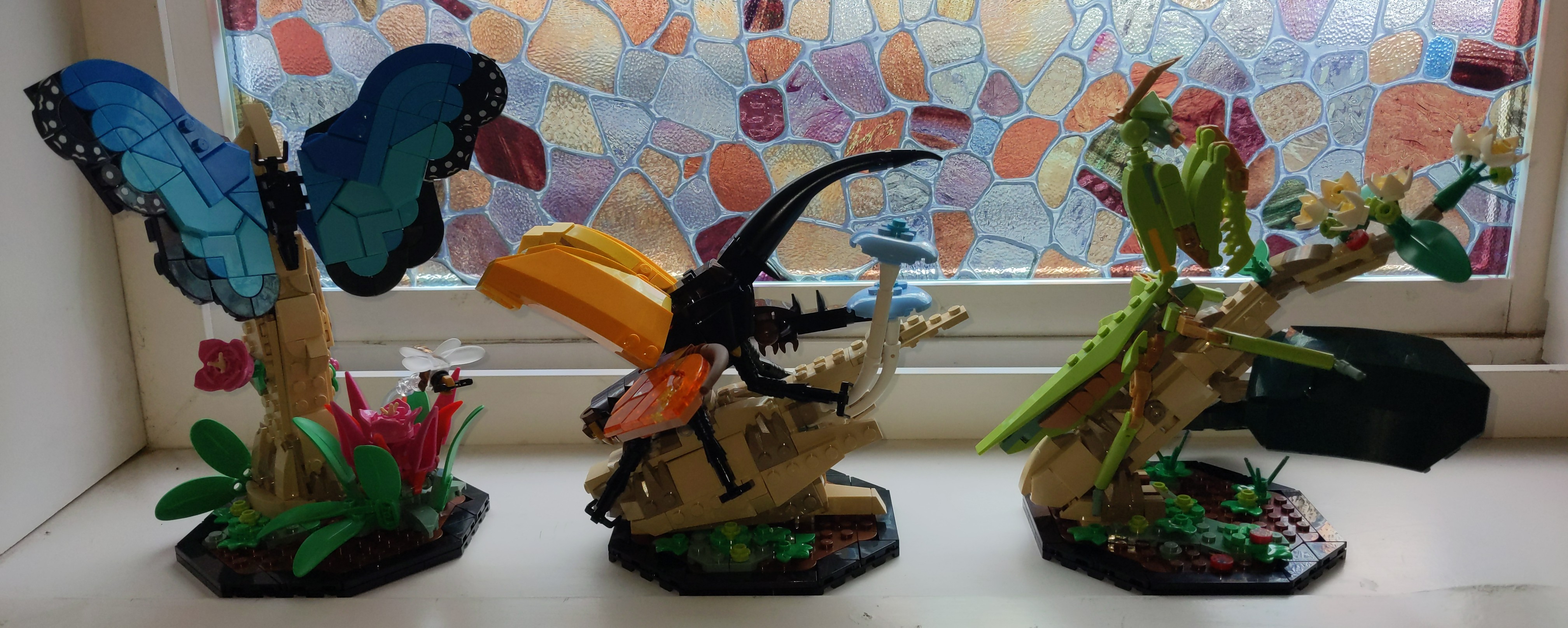 Roughly to-scale sized Lego models of a blue morpho butterfly, a hercules beetle, and a chinese mantis.