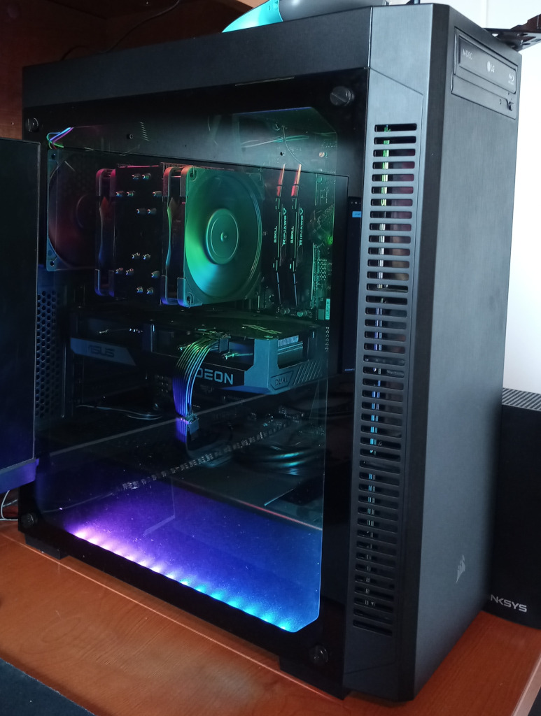 My computer tower. The CPU heatsink, graphics card, and RAM are prominently visible through the glass side panel. An optical drive is also visible on the front.